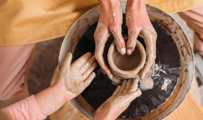 Adult and child using a pottery wheel together