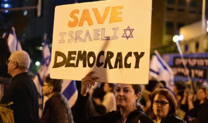 Woman holding a sign reading 'Save Israeli Democracy'