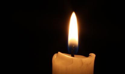 Single lit candle against a dark background